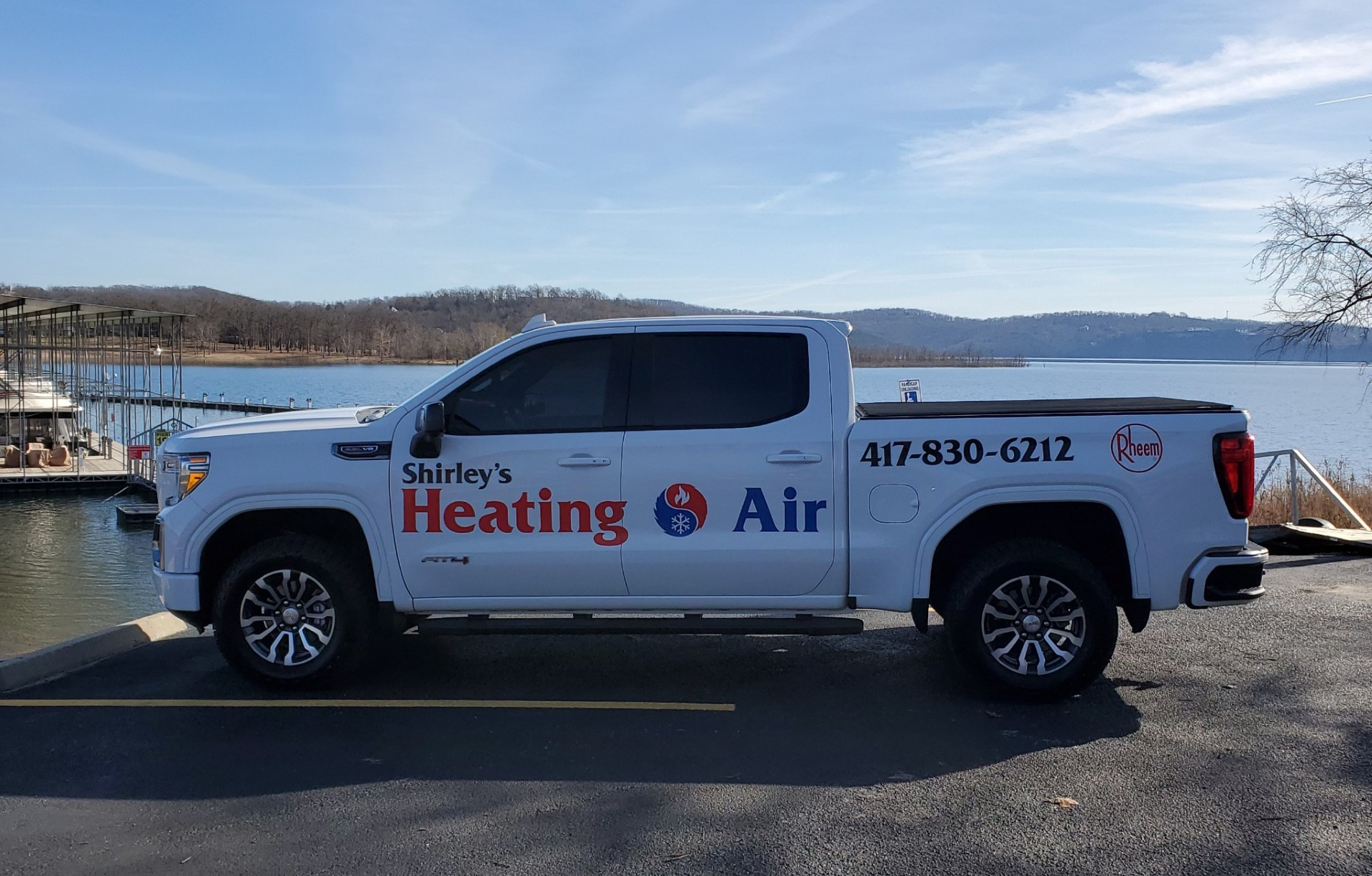 White Heating & Air service van parked by the water with mountains in the background