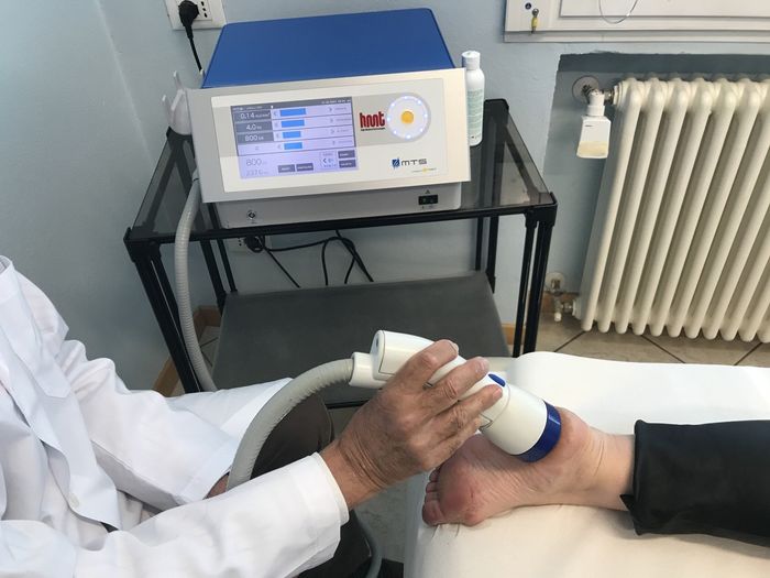 Un medico sta usando una macchina sul piede di un paziente.