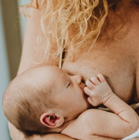 Una donna allatta il suo bambino tra le braccia.
