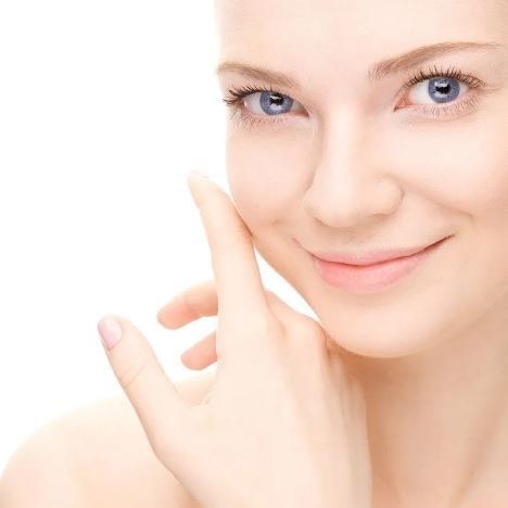 Una donna dagli occhi azzurri si tocca il viso con la mano.