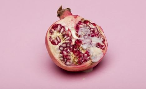 Un melograno è tagliato a metà su uno sfondo rosa.