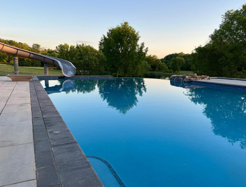 A large swimming pool with a slide in the background