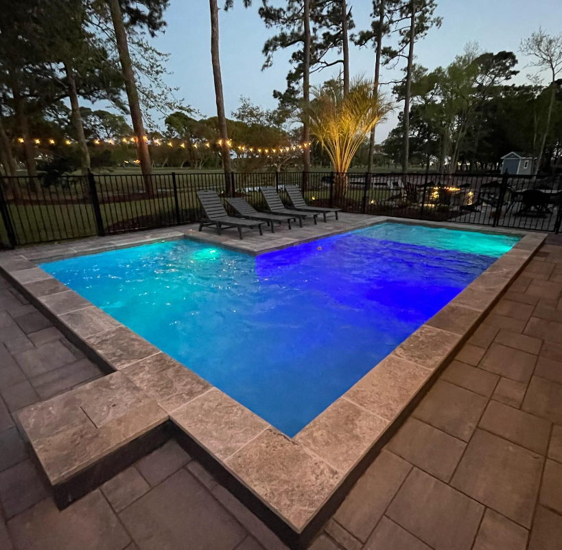 A large swimming pool surrounded by chairs and trees