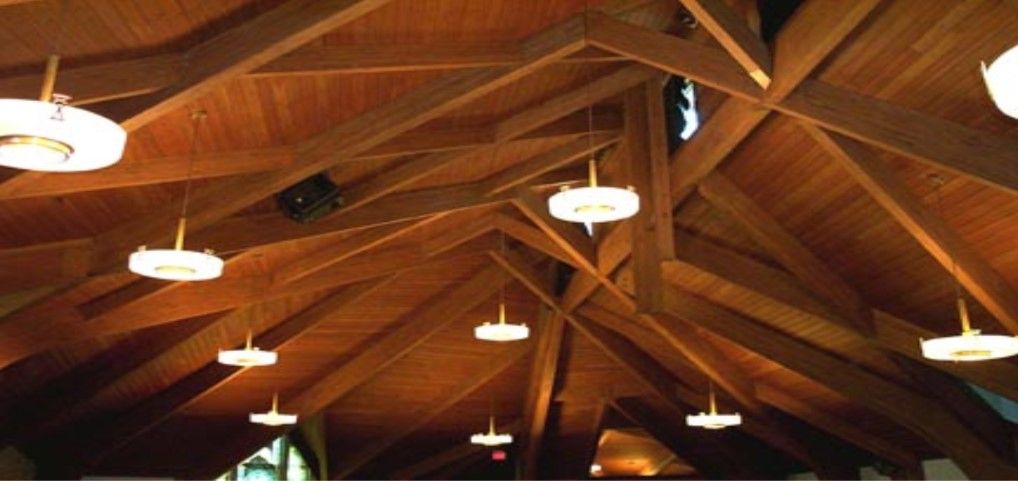 Wooden church ceiling with exposed beams and pendant lights.
