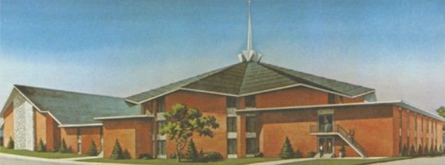 Brick church building with a steeple, set under a blue sky.