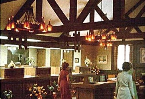 Bank interior with people near teller windows and wooden beams.