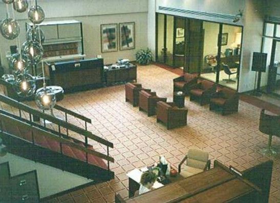 Lobby with tiled floor, seating areas, stairs, and a reception desk. Neutral colors, natural light.