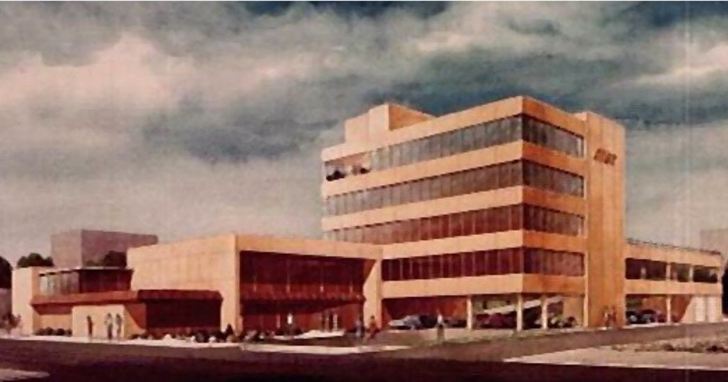 Mid-century modern-style building with multiple stories and large windows under a cloudy sky.