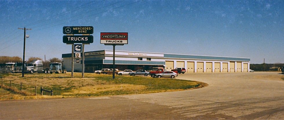 A truck and auto sales business with signs in a rural setting.