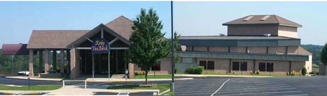 Two-building complex with parking lots and a tree. One building has a gabled roof, the other is multi-tiered.