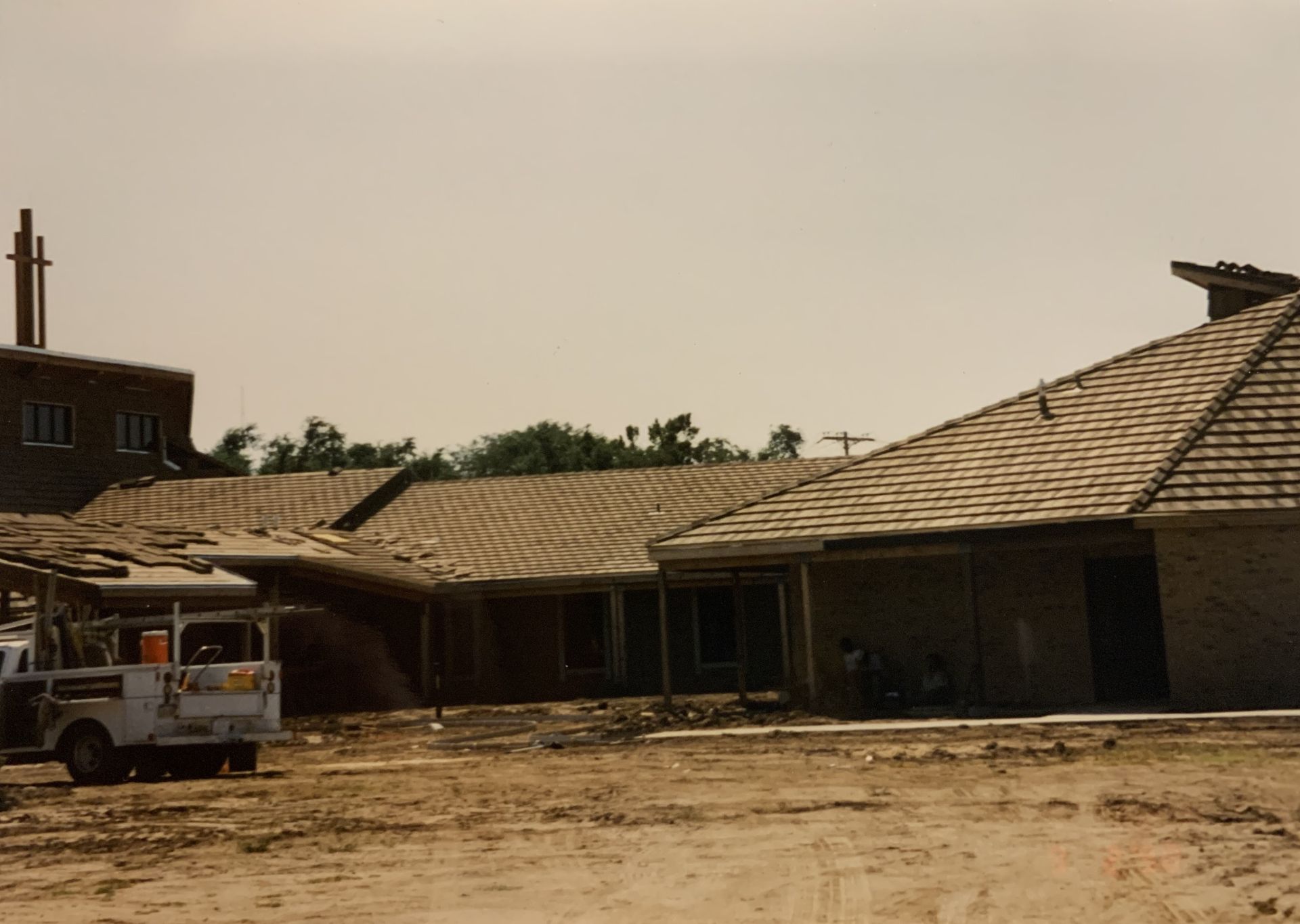 Construction site with building having tiled roofs; a truck is parked nearby.
