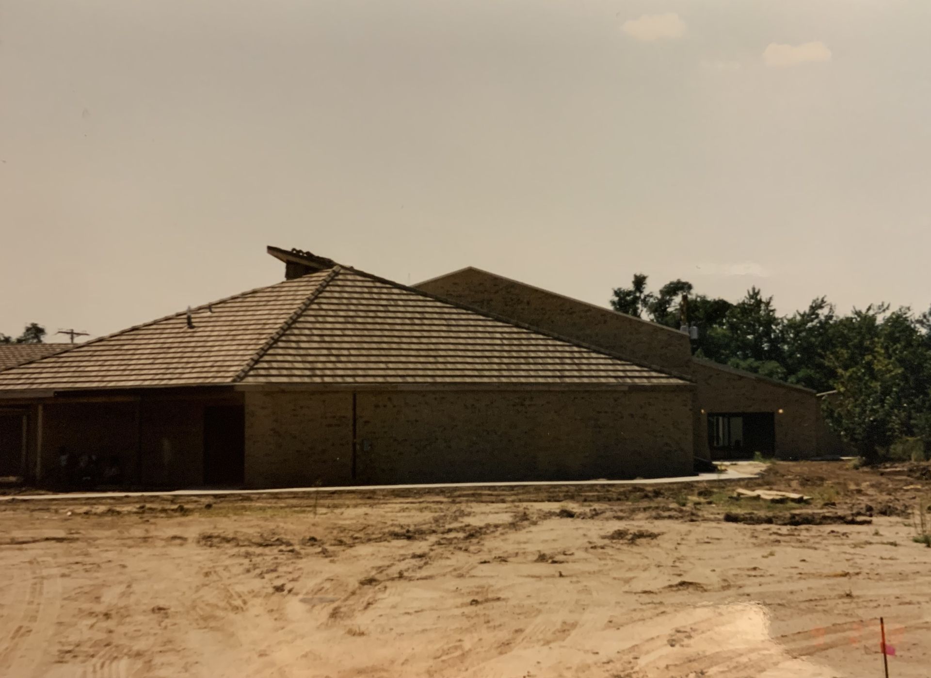 Low-angle shot of a brick building with a tiled roof under a hazy sky. Construction site in the foreground.