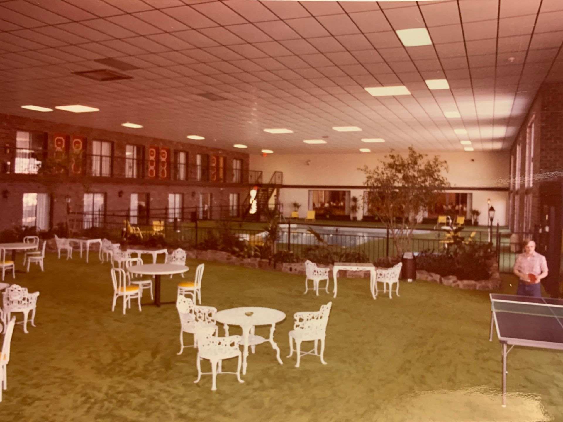 Indoor courtyard with tables, chairs, and a ping pong table.