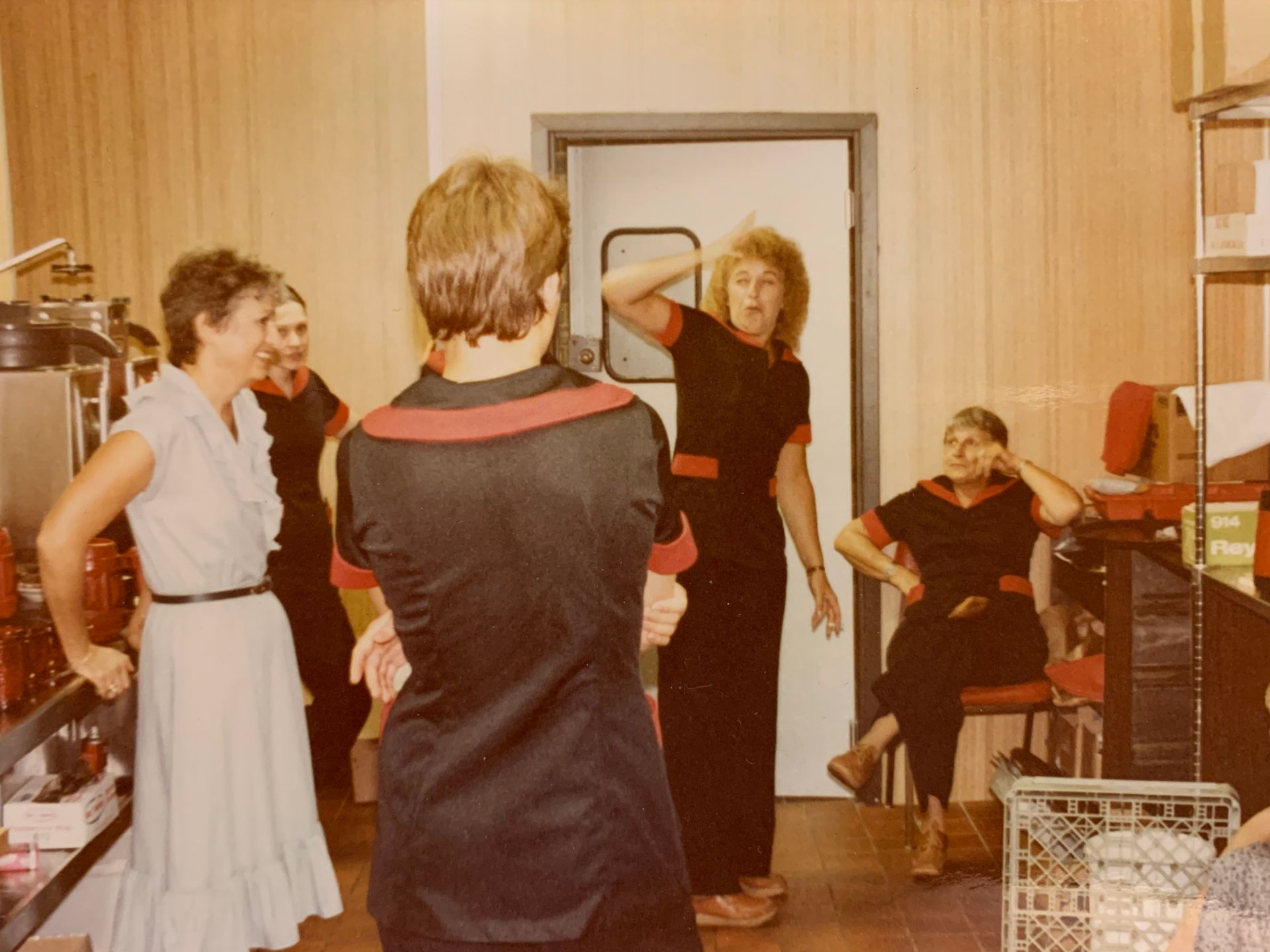 People in matching uniforms and a woman in a dress inside a brightly lit business.