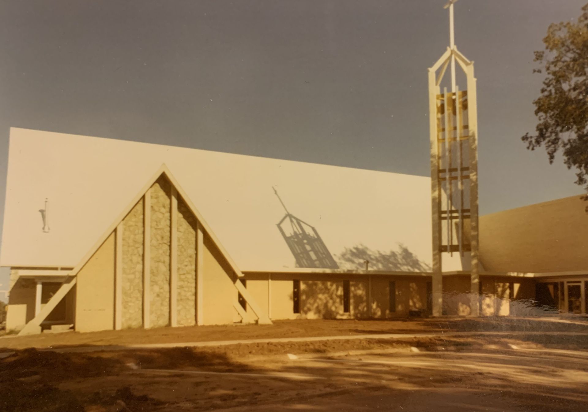 Modern church building with angled roof, stone facade, and a bell tower.