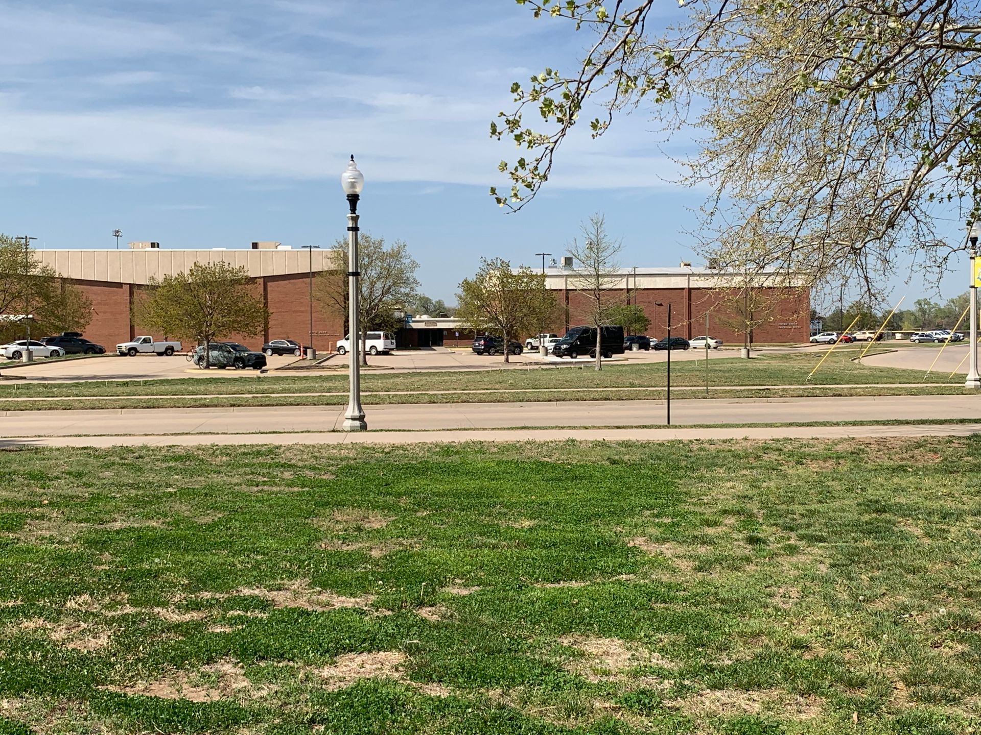 Large brick building with parking lot and trees on a sunny day.