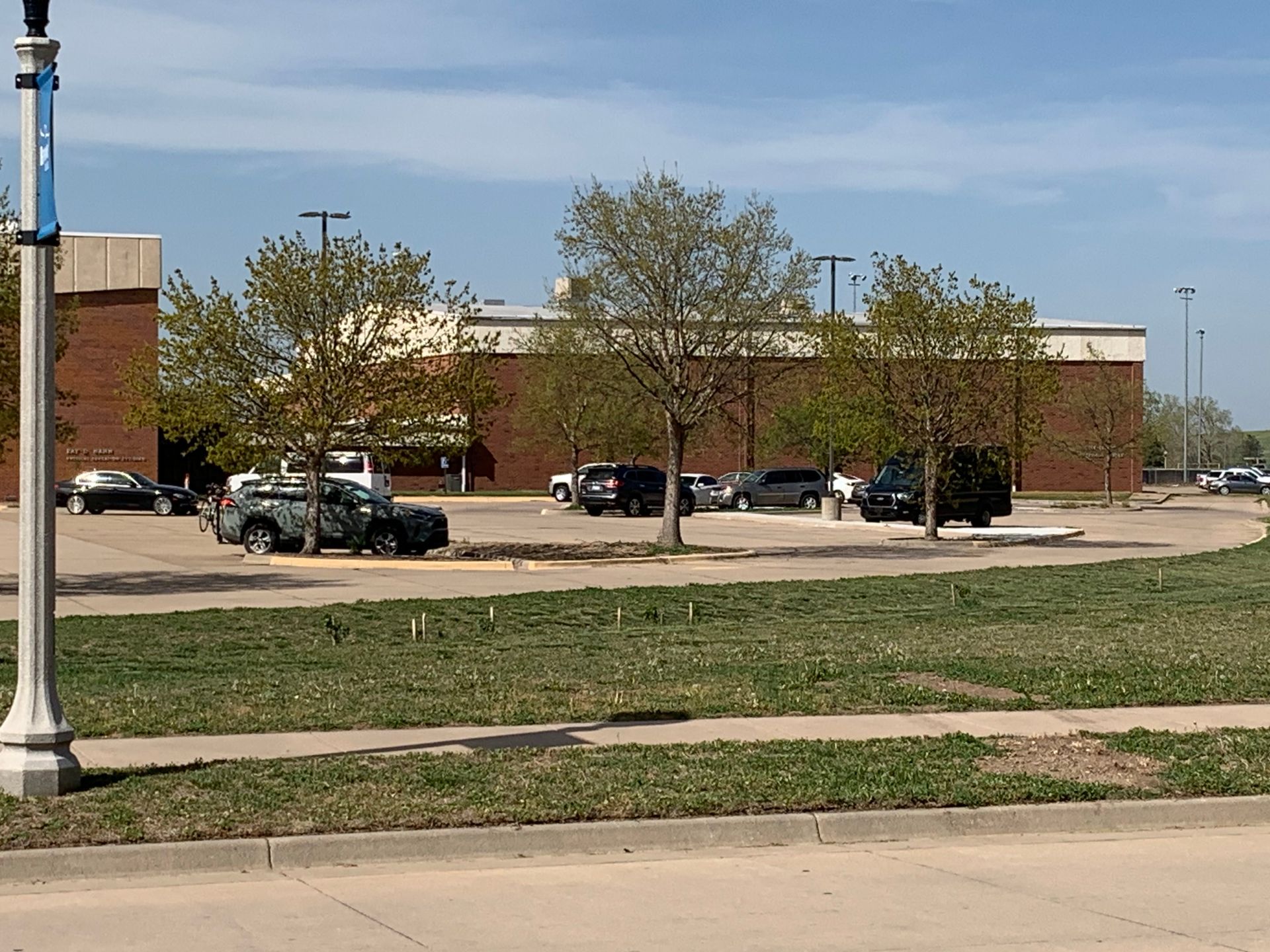 Parking lot with cars in front of a brick building on a sunny day.