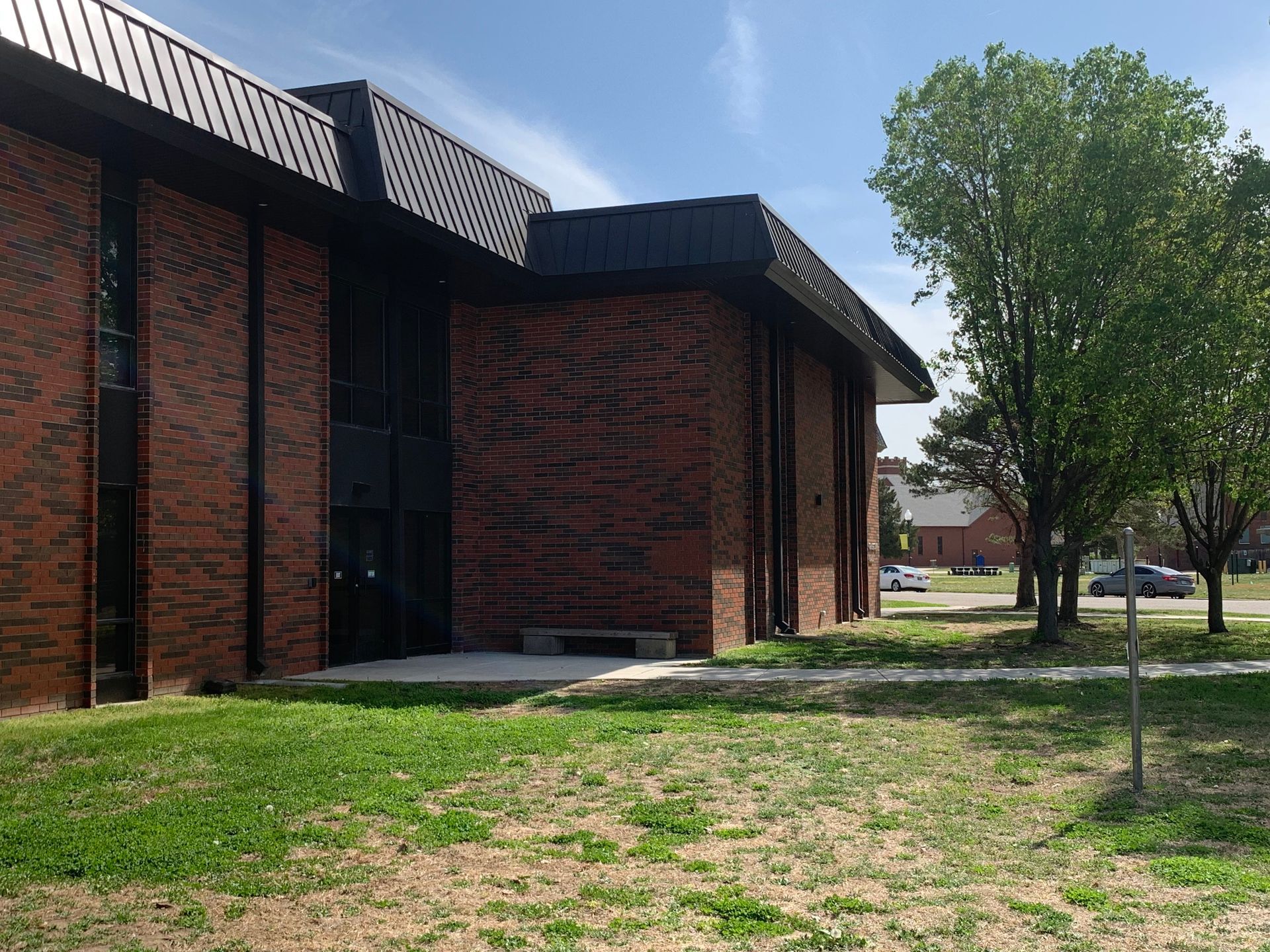 Brick building with black trim, angled roof, and a grassy area in front.