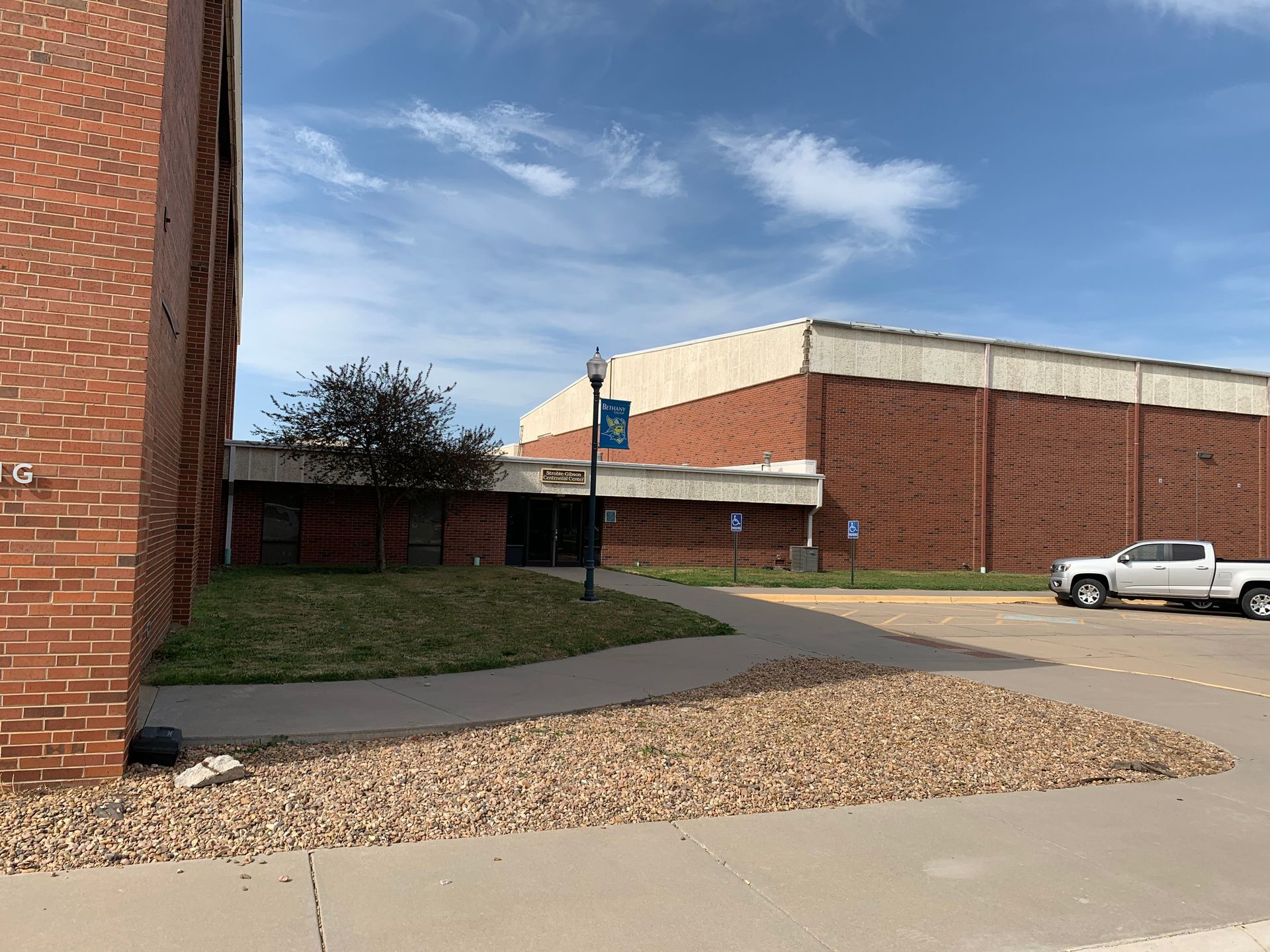 Brick buildings and a walkway leading to a building entrance; a white truck is parked nearby.