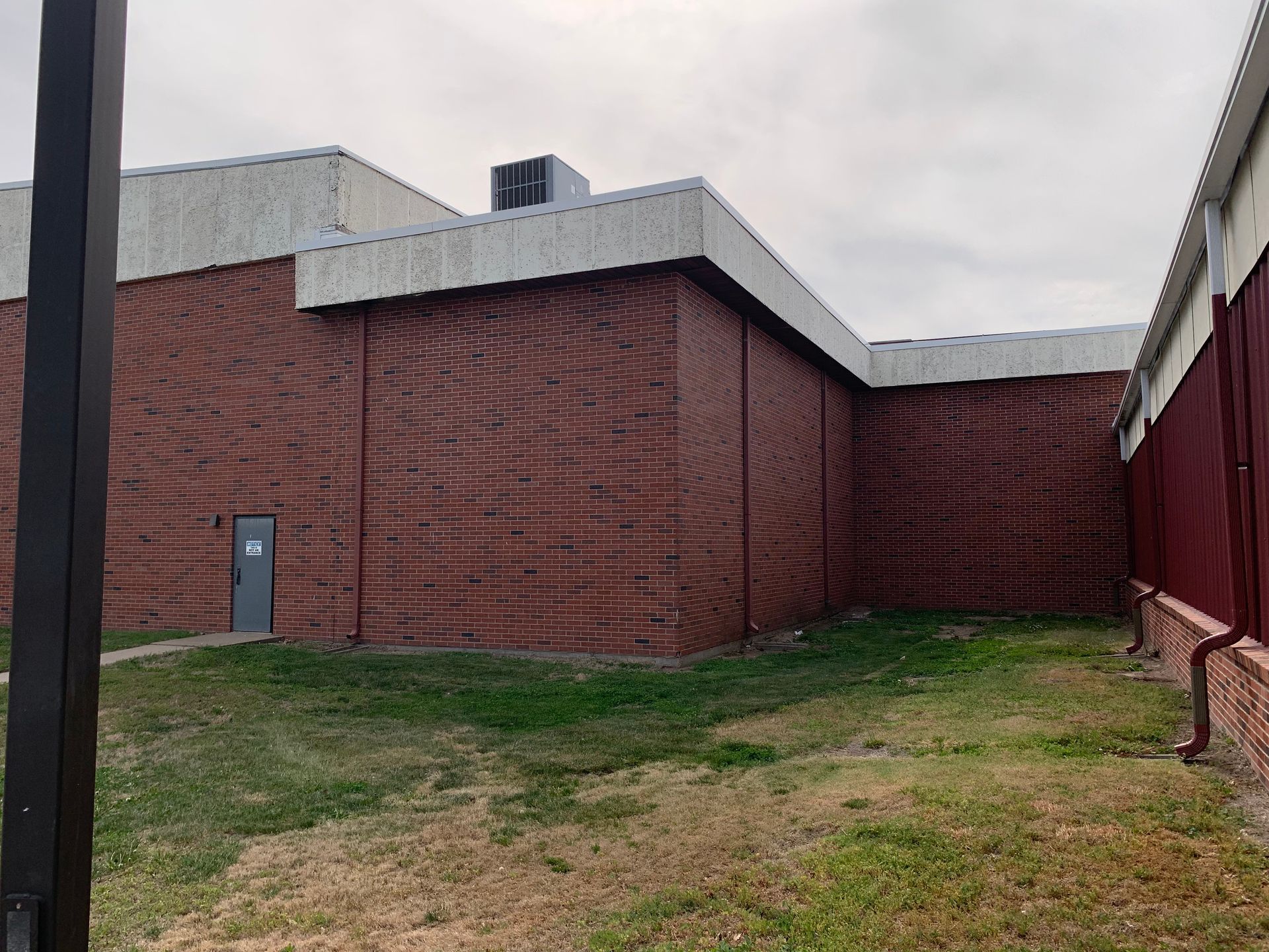 Red brick building exterior with white trim and a small grassy area.