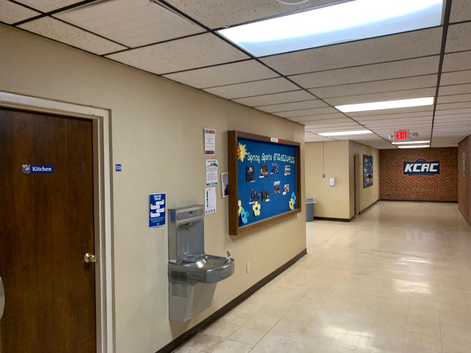 Hallway with water fountain, bulletin board, and a door labeled