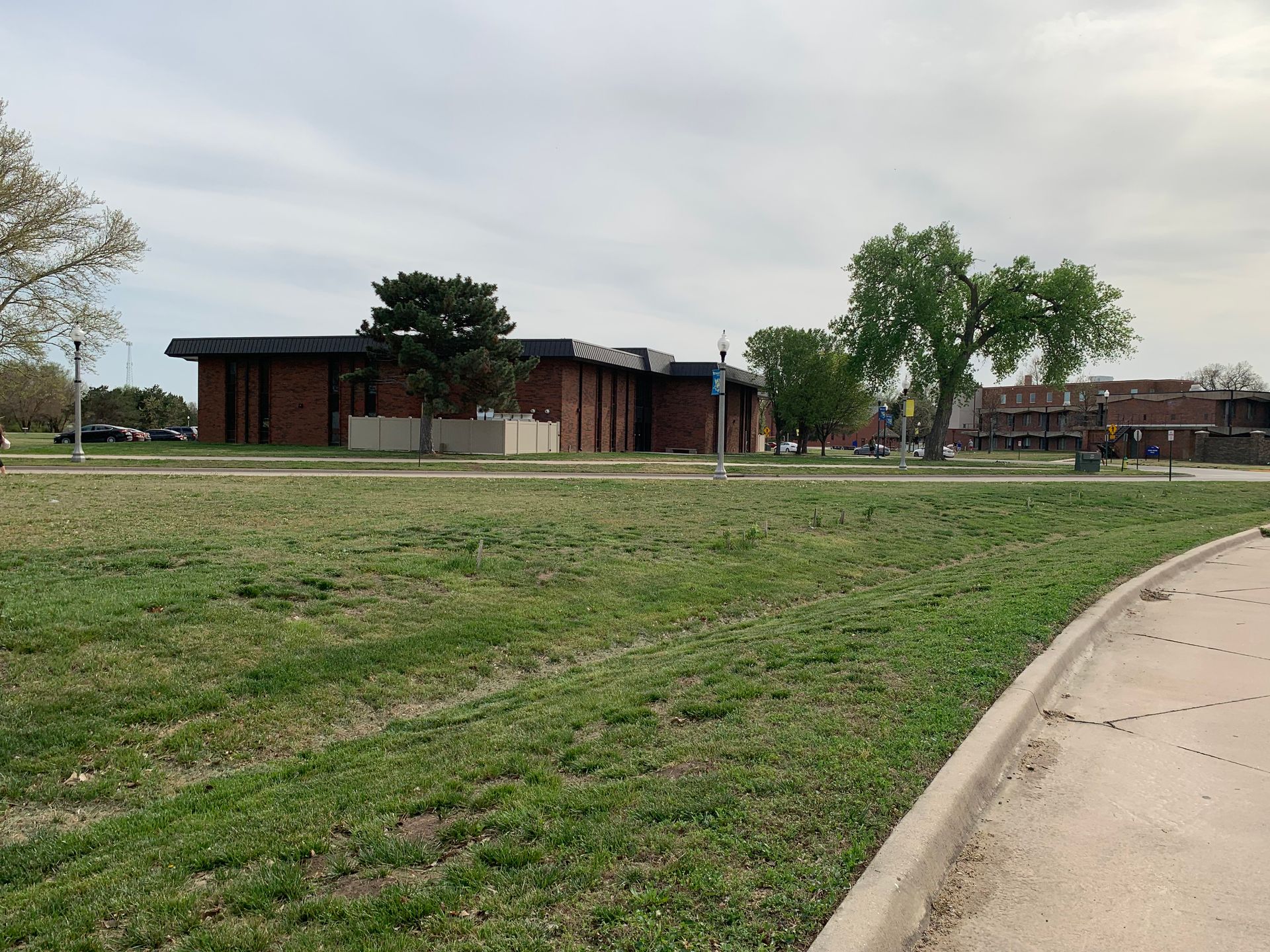 A low brick building with a flat roof on a grassy field under a cloudy sky.