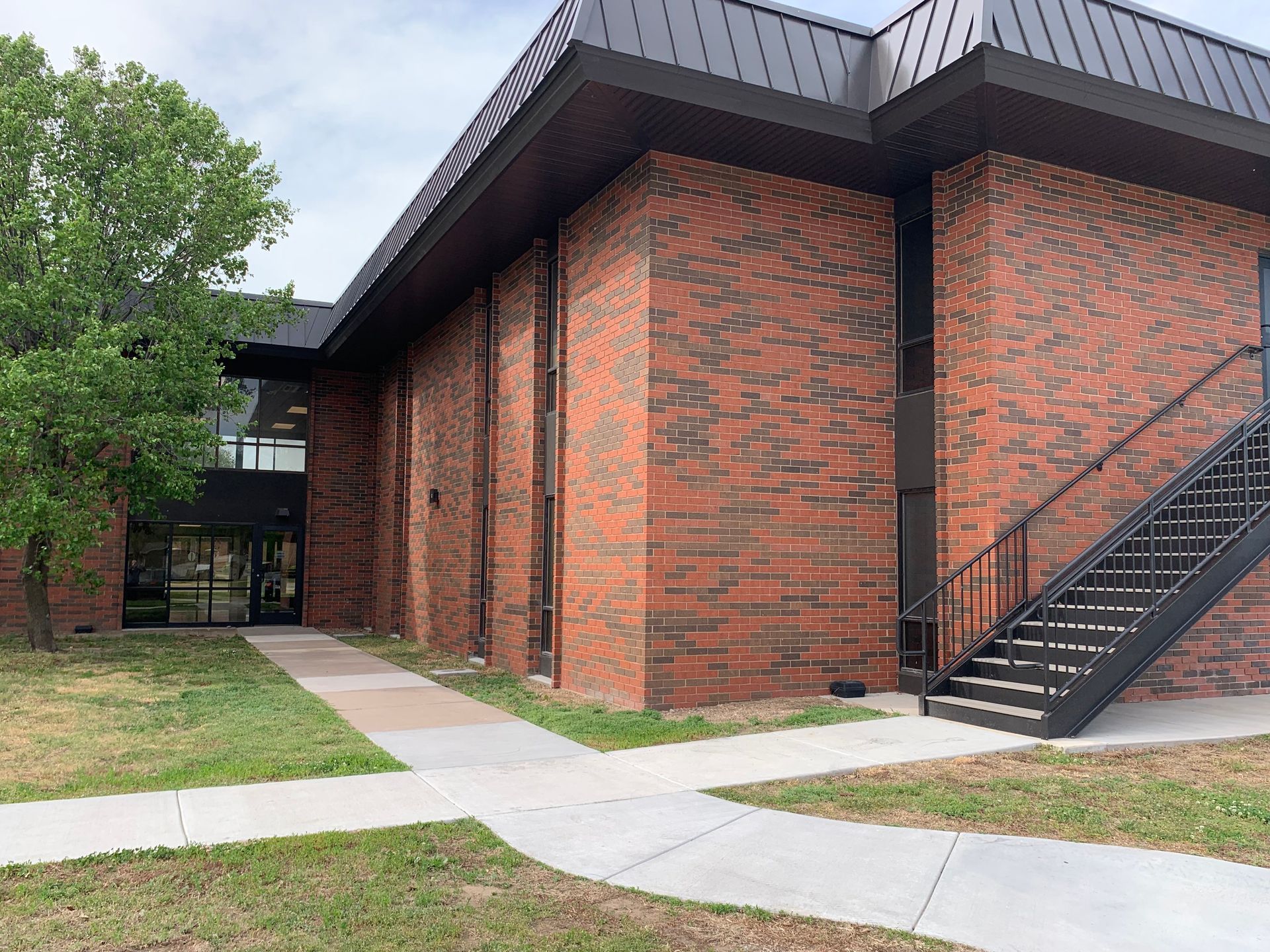Brick building with black trim, walkway, and exterior staircase.