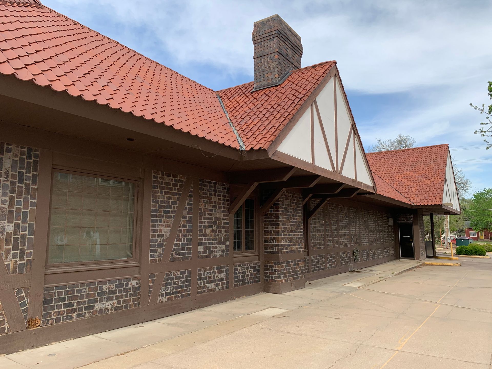 Brown brick building with red tile roof and a chimney.