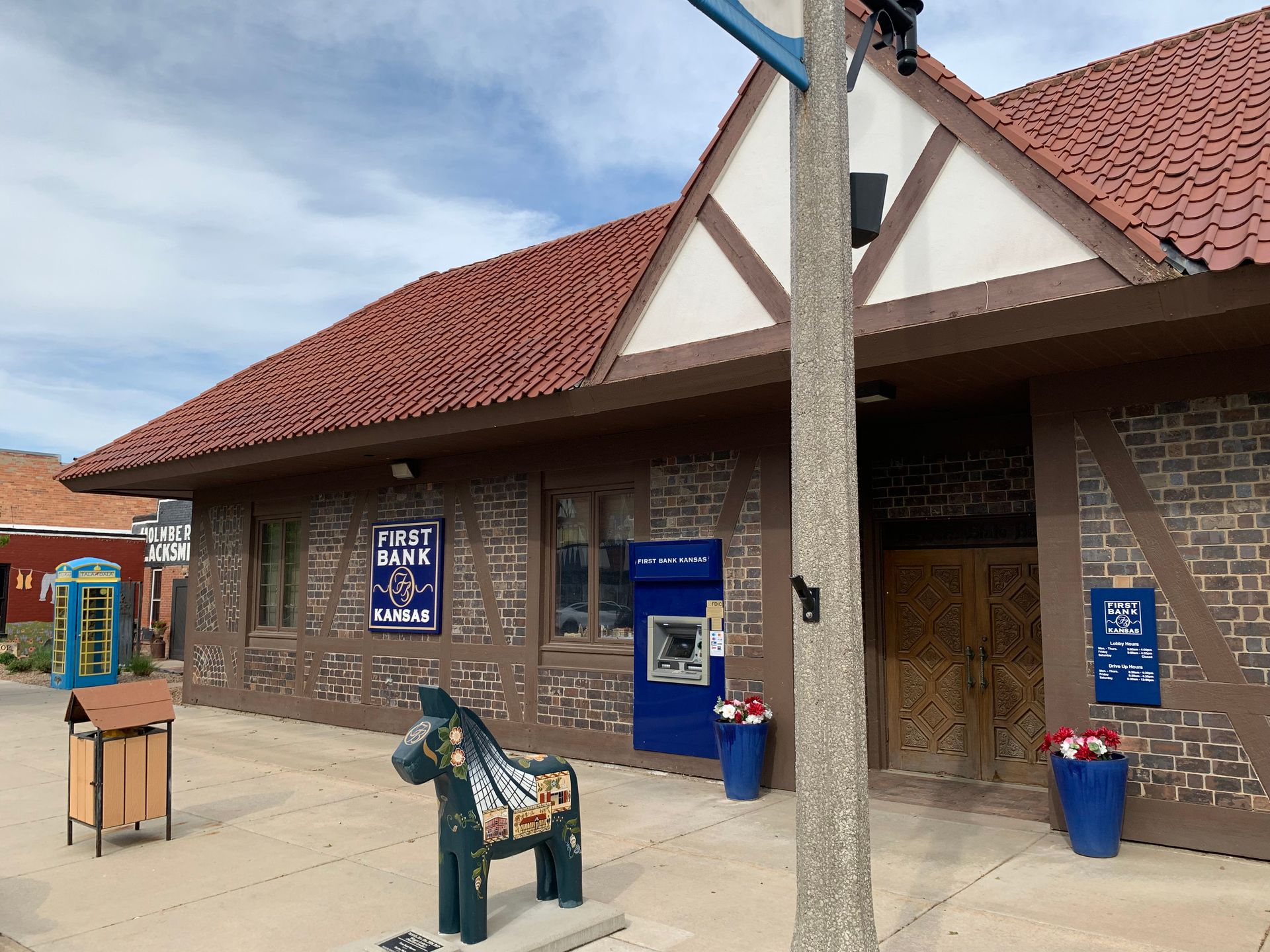Exterior view of Public Bank building with decorative facade, ATM, and horse sculpture on a sidewalk.