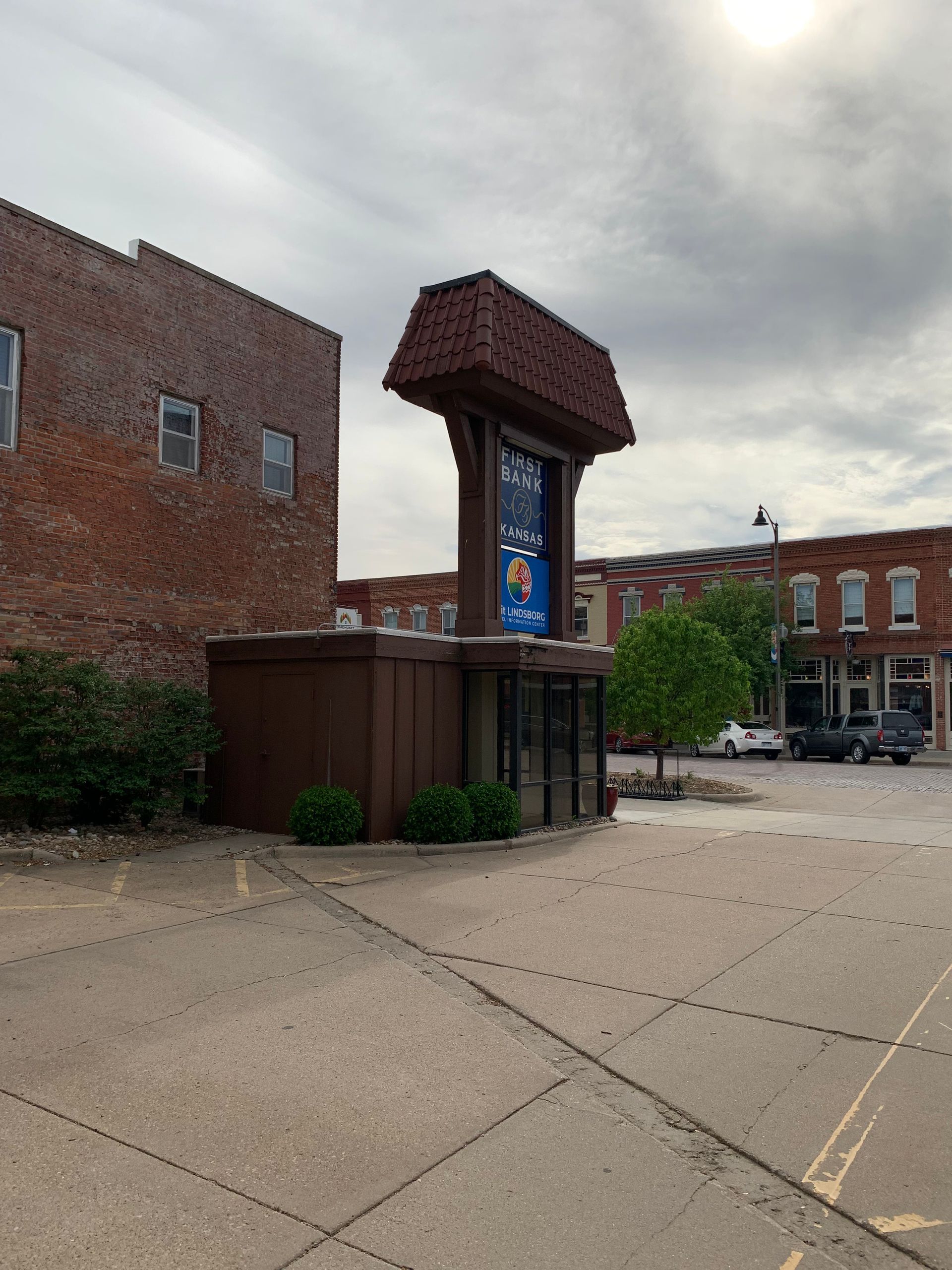Brown building with a tall sign and storefront, next to a brick building, overcast sky.