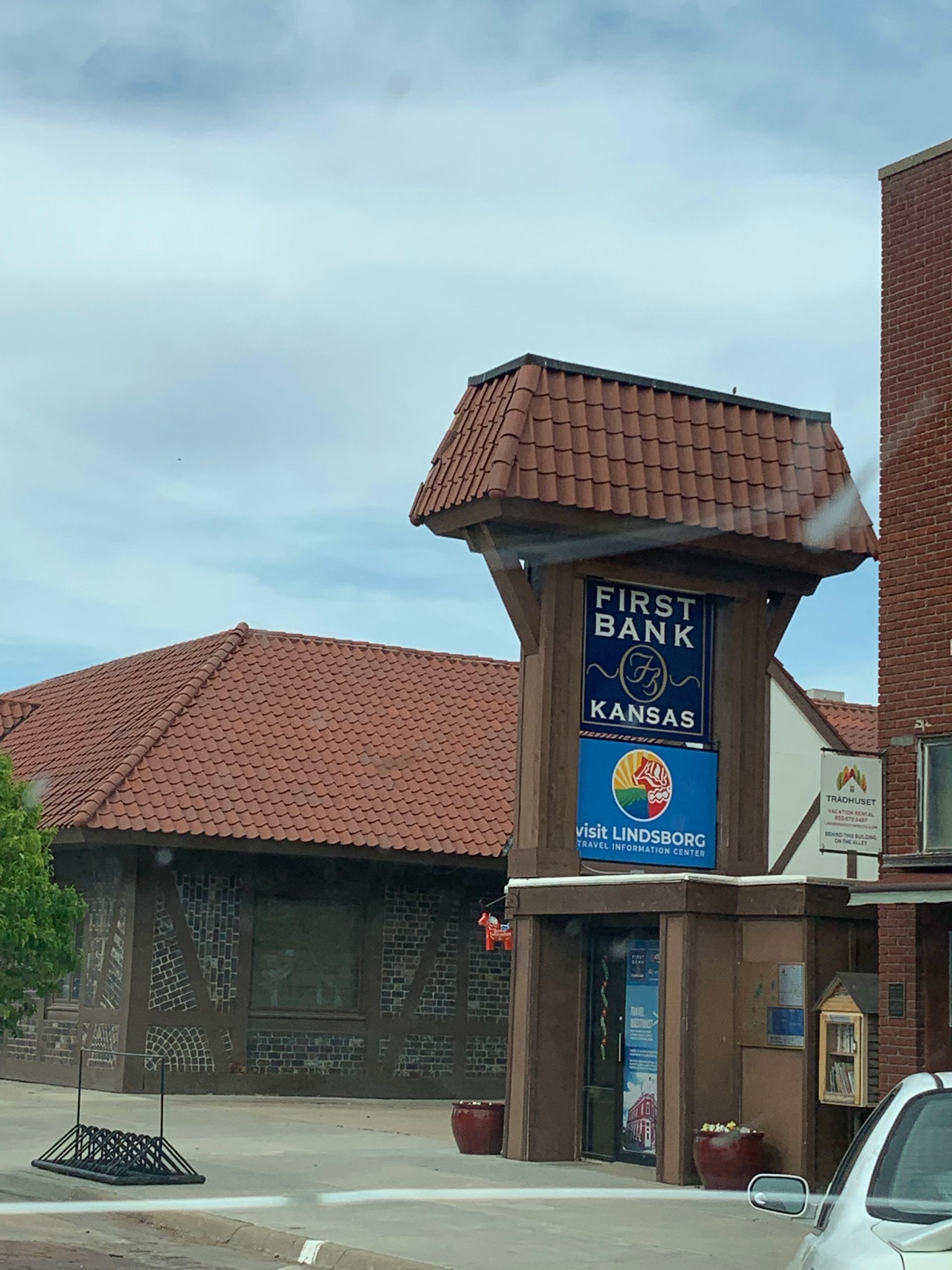 First Bank Kansas sign with red-tiled roof, set against a cloudy sky.