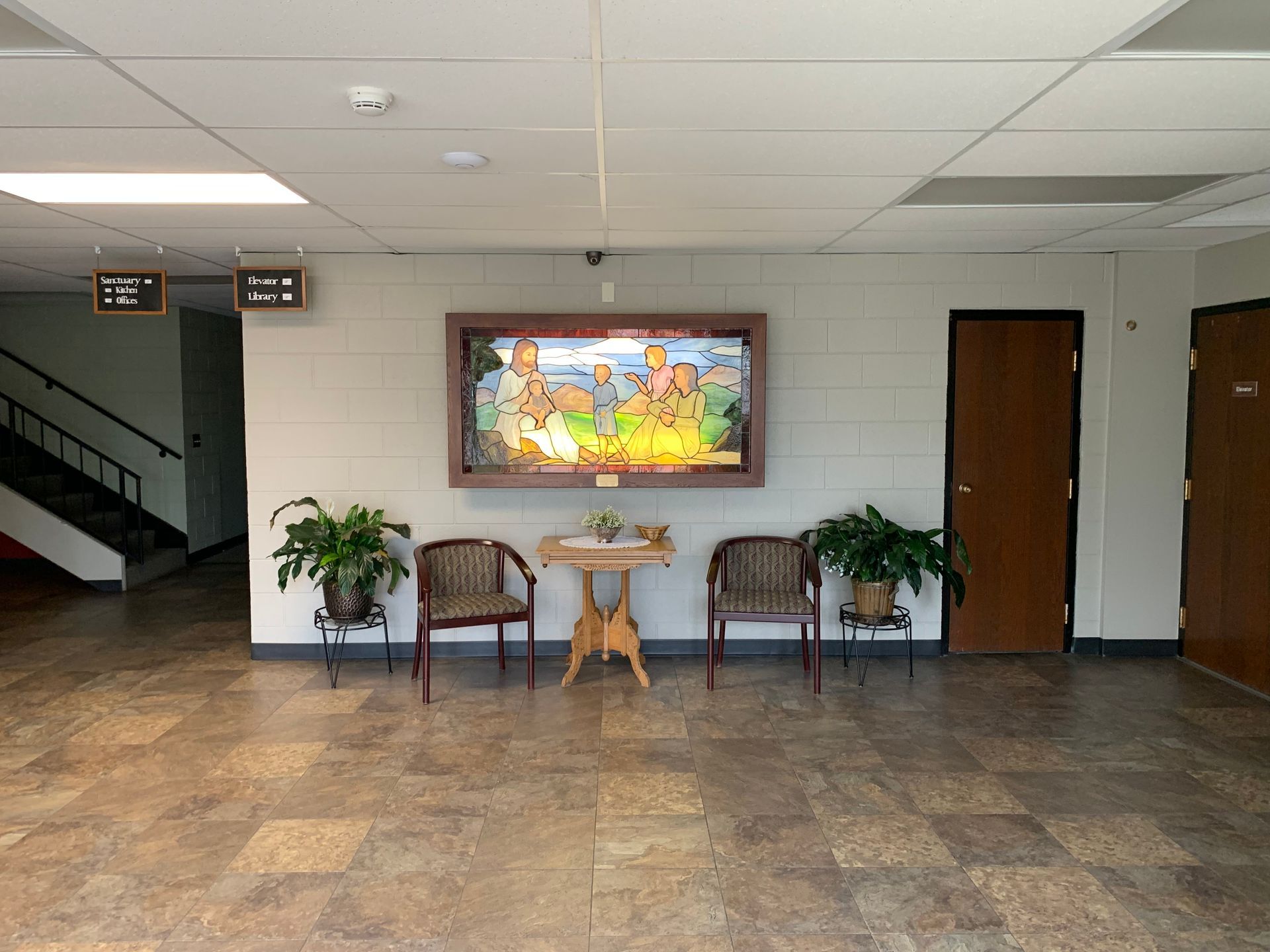 Hallway with artwork, chairs, and potted plants.