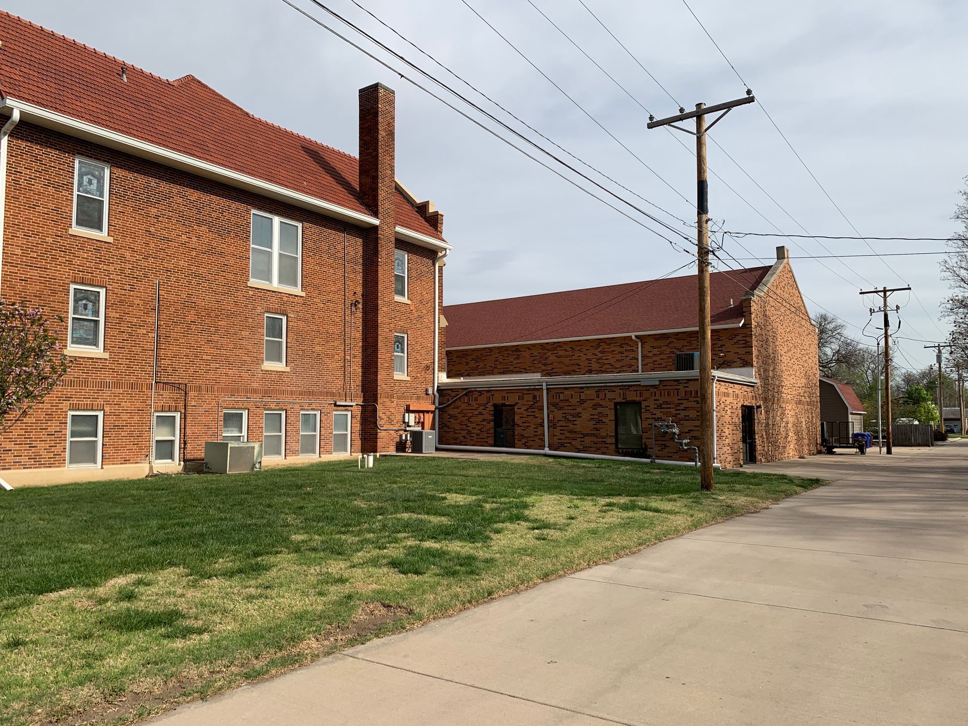 Red brick buildings with red tile roofs, green grass, and a paved street.