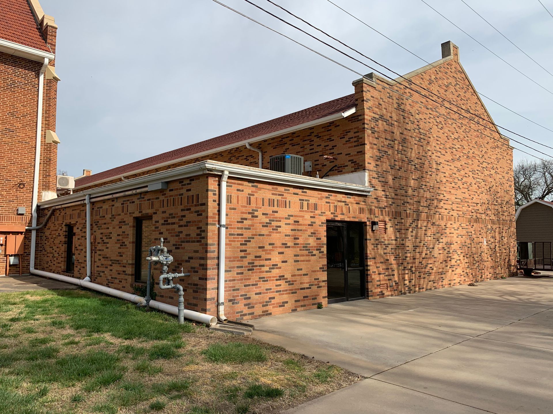 Red brick building with a flat roof, white gutters and a black door; exterior view.