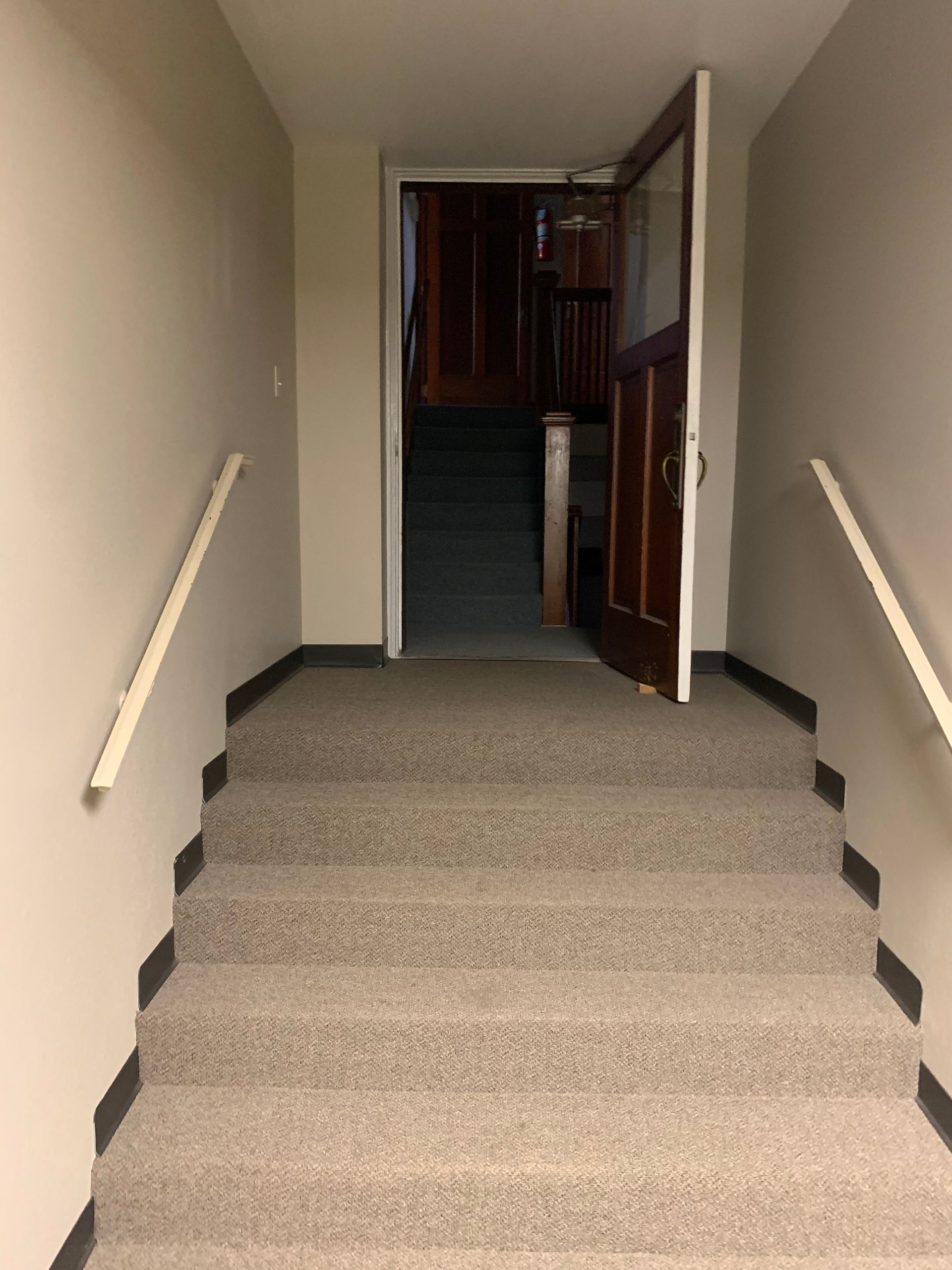 Staircase leading up to an open door; handrails on either side.