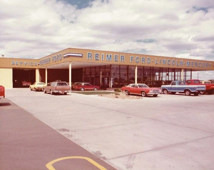 Reimer Ford Lincoln Mercury dealership with various cars displayed; sunny day.