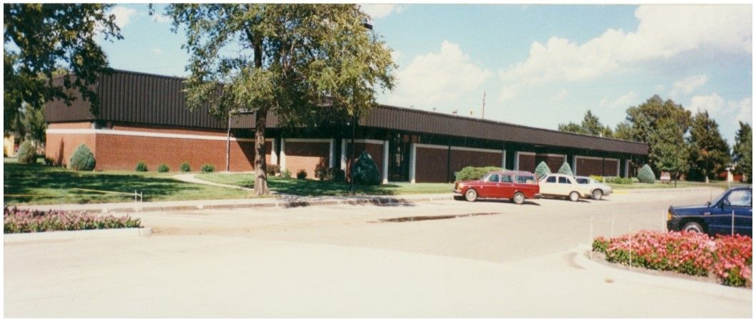 Building with brick exterior and dark roof. Cars parked in front.
