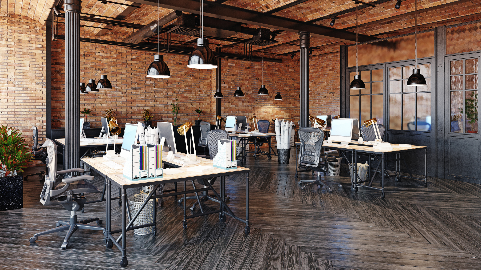 Open-plan office with desks, computers, and chairs; exposed brick walls and ceiling; industrial-style lighting.