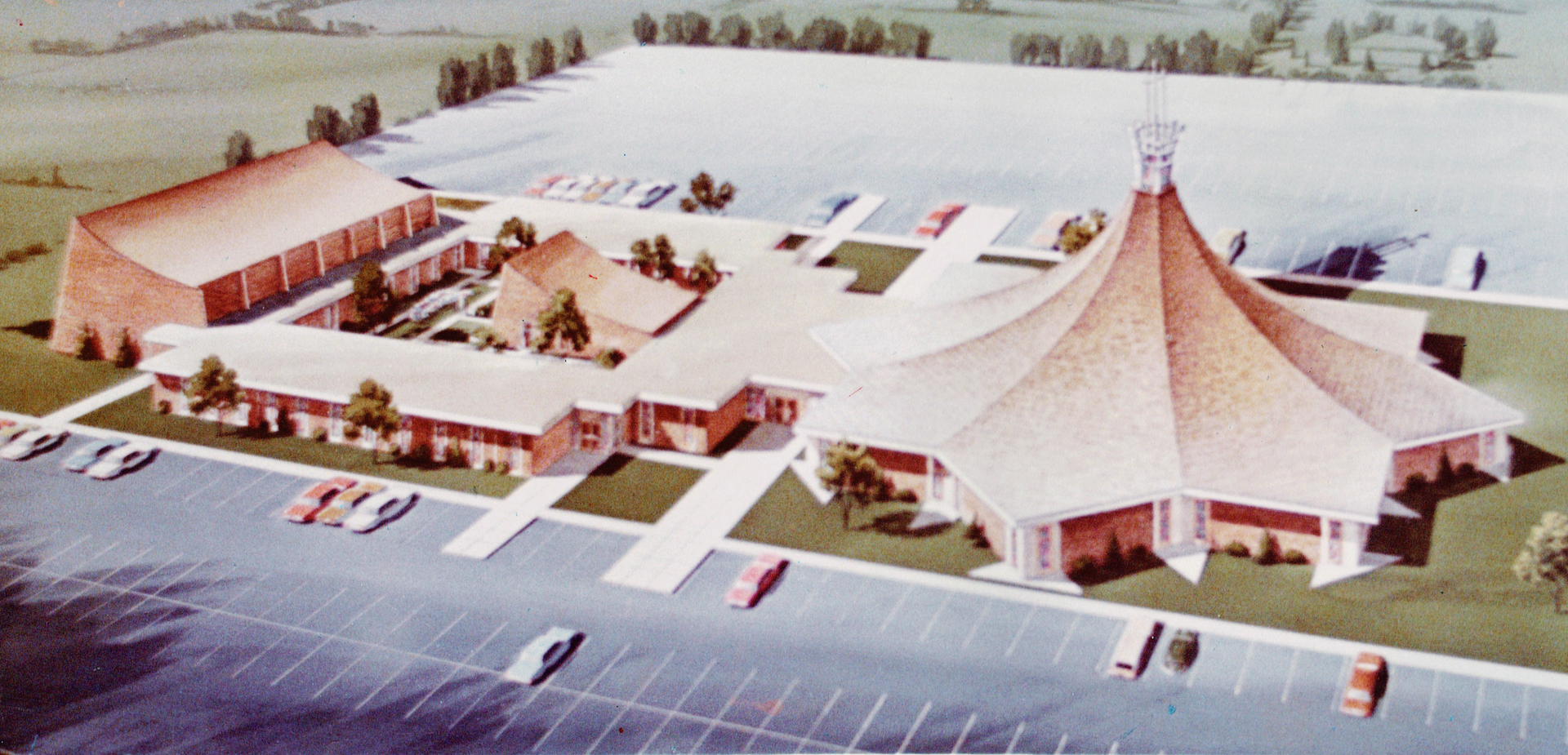 An aerial view of a church complex with a large, tent-like roof and parking lot.