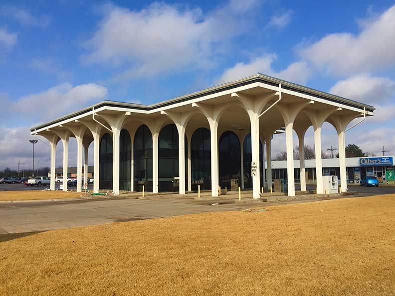 White-columned building with large arched windows under a light roof; sunny day.