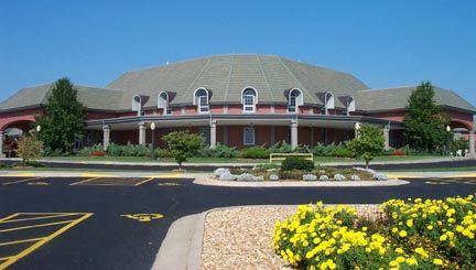 Large brick building with a domed roof and arched windows; blue sky.