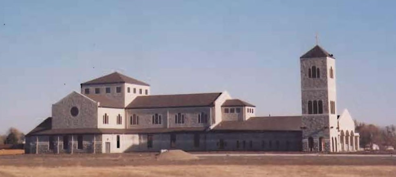A large, stone building with a tall bell tower under a blue sky.