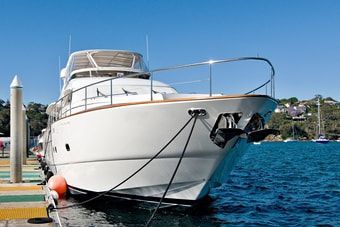 Large yacht exterior with a teak lined bow, docked in a marina