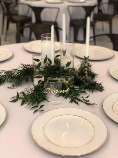 Elegant banquet table with white plates, candles, and a green floral centerpiece