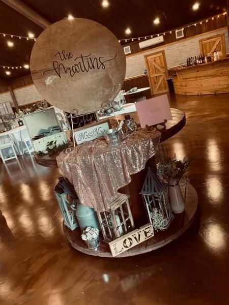 Decorated welcome table on a shiny floor, with sign reading “The Andersons” at a reception venue
