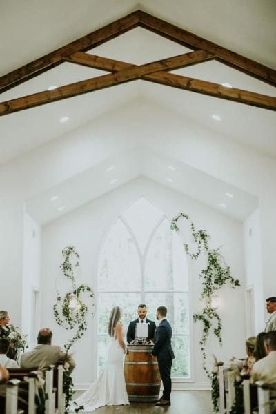 Wedding ceremony in a white chapel with the couple at the altar and guests seated on both sides