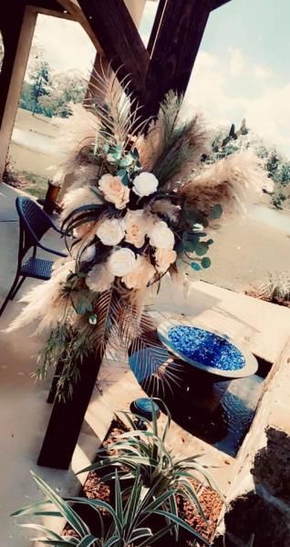 Floral arrangement with white and dark pink flowers on a wooden post near a blue planter outdoors