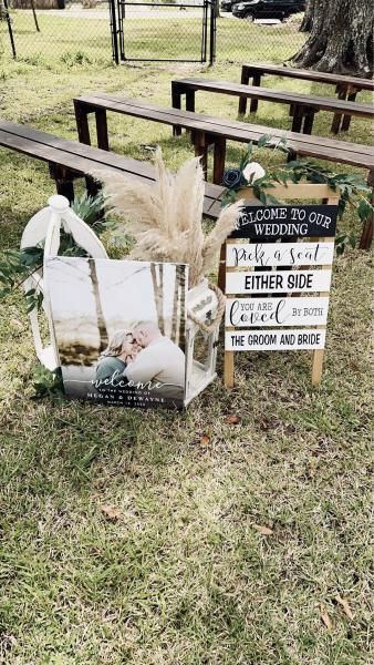 Memorial display with flowers and a sign reading “Please do not vote here,” beside picnic tables in a park.