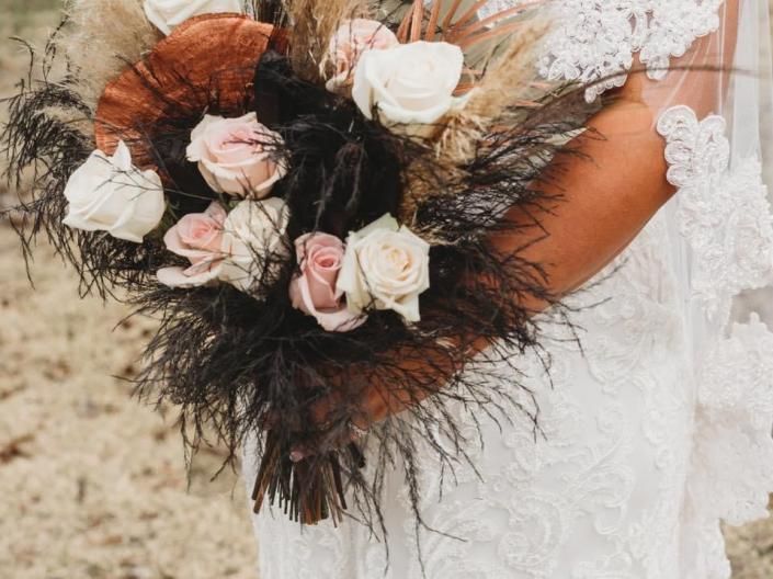 Bride holding a white and blush rose bouquet against a lace wedding dress