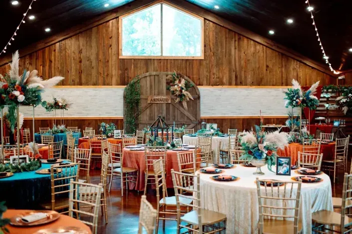 Rustic barn wedding reception with round tables, string lights, and floral centerpieces